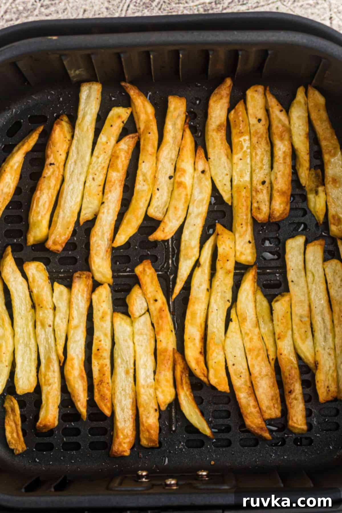 Crispy Air Fryer French Fries 6 Golden French fries in an air fryer basket after being seasoned and air fried.