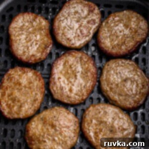 Perfect Air Fryer Sausage Patties 7 Juicy brown sausage patties in the air fryer basket after being cooked.