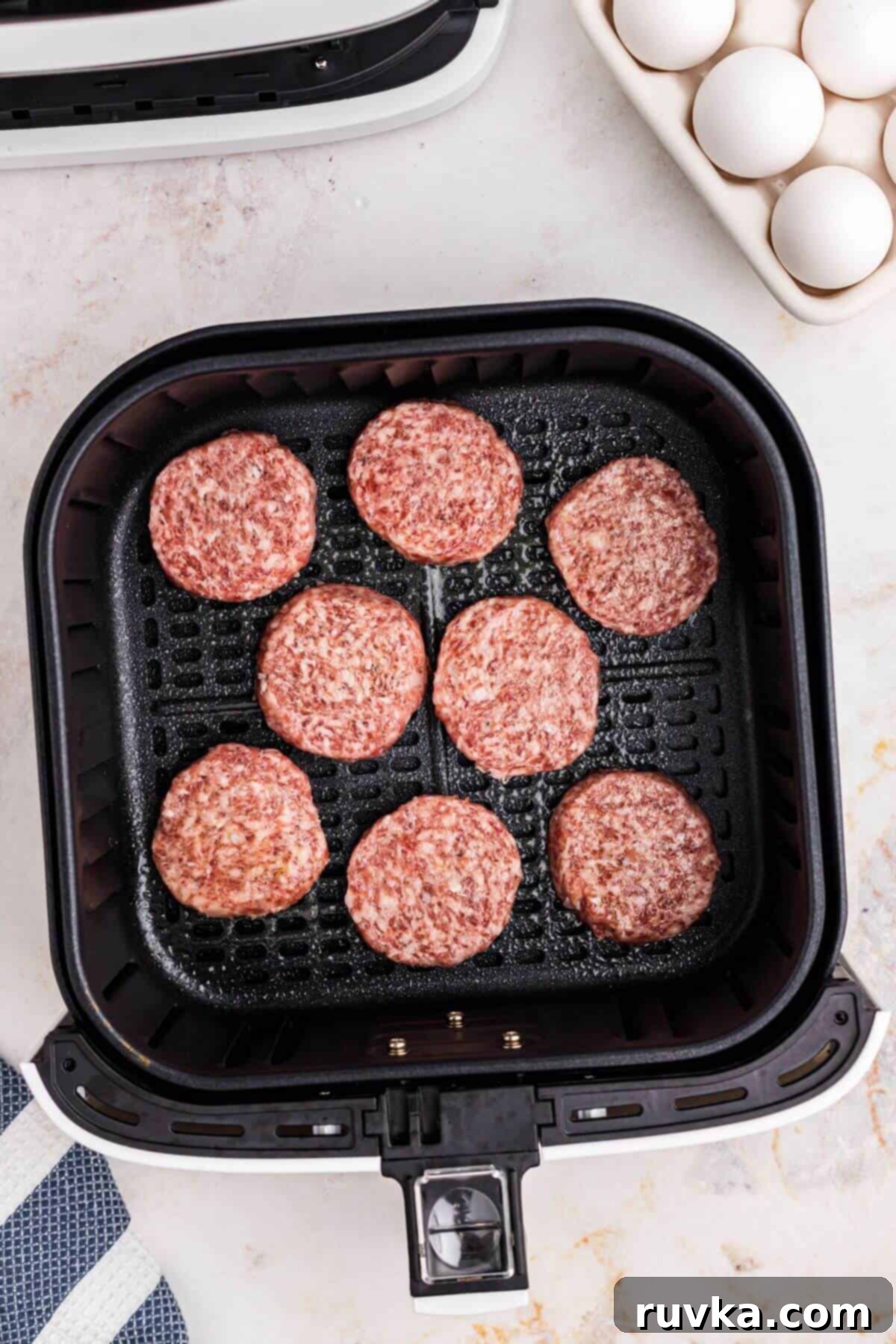 Perfect Air Fryer Sausage Patties 4 sausage patties in the basket of the air fryer, ready to be cooked.