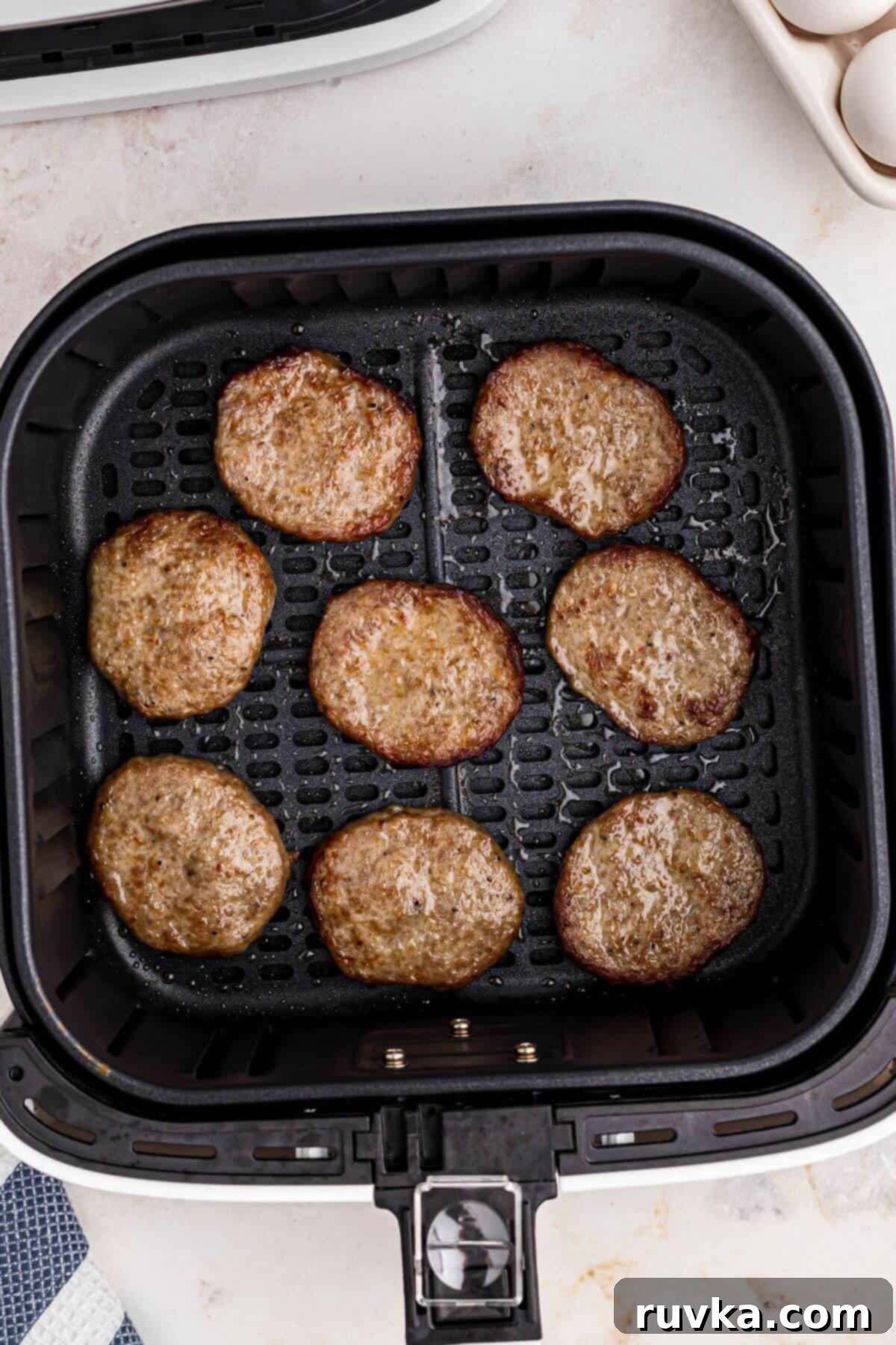 Perfect Air Fryer Sausage Patties 5 sausage patties in the basket of the air fryer.