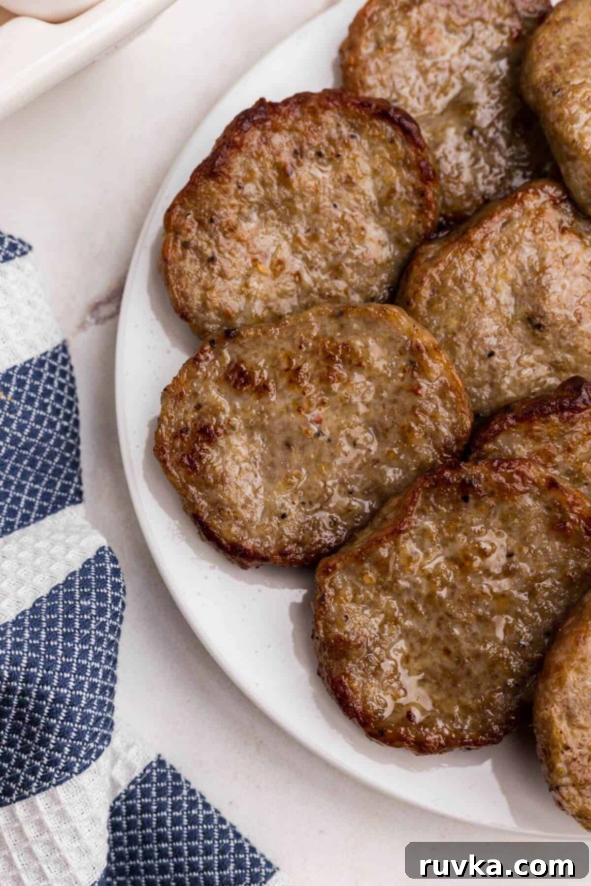 Perfect Air Fryer Sausage Patties 6 Juicy sausage patties after being cooked in the air fryer, stacked on a white plate.