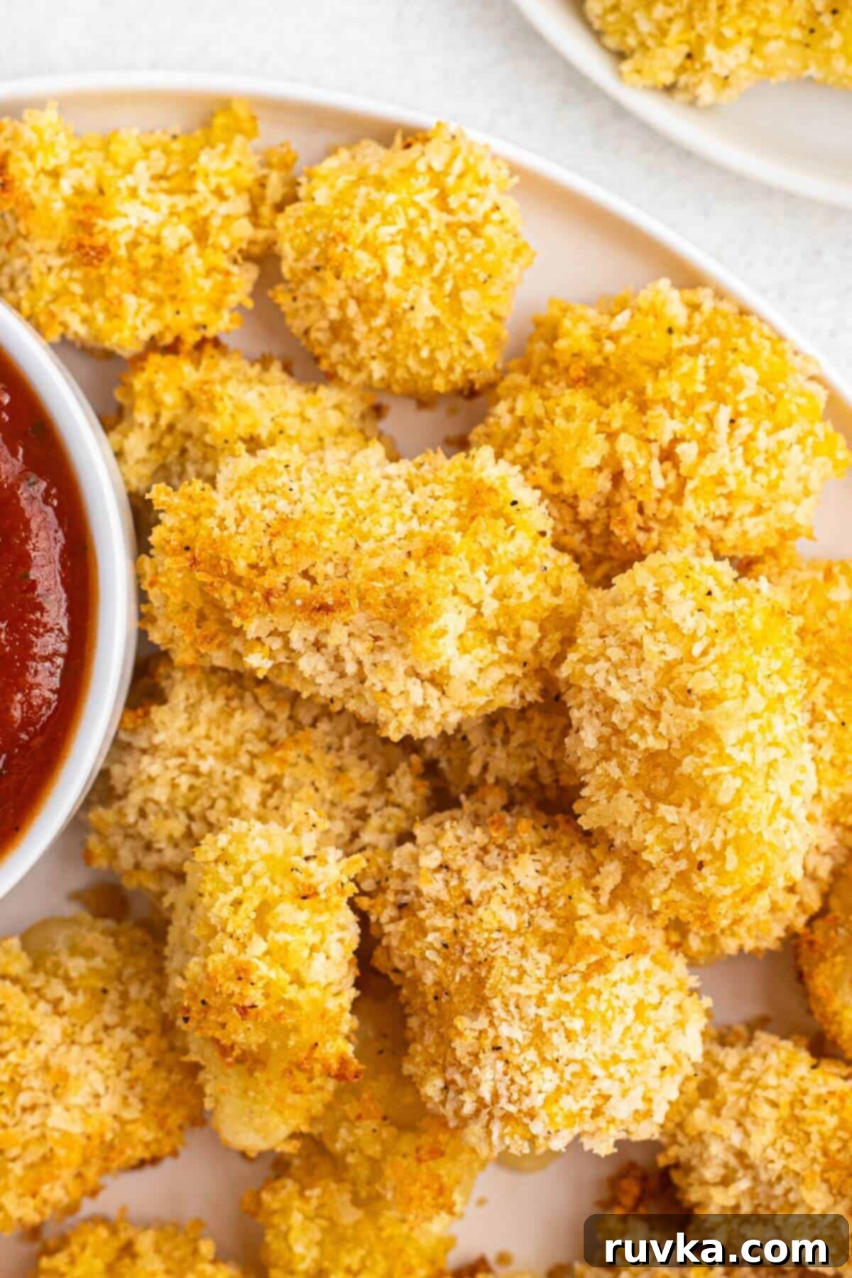 Crispy Air Fryer Cheese Curds 3 Golden battered cheese curds stacked on a white plate.