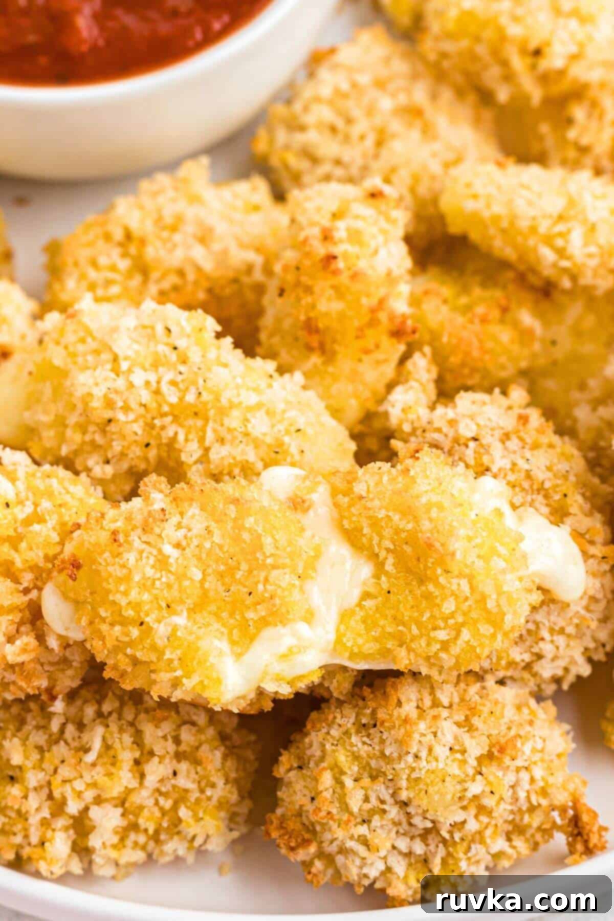 Crispy Air Fryer Cheese Curds 8 Crispy golden fried cheese curds stacked on a plate with melted cheese pulled out.