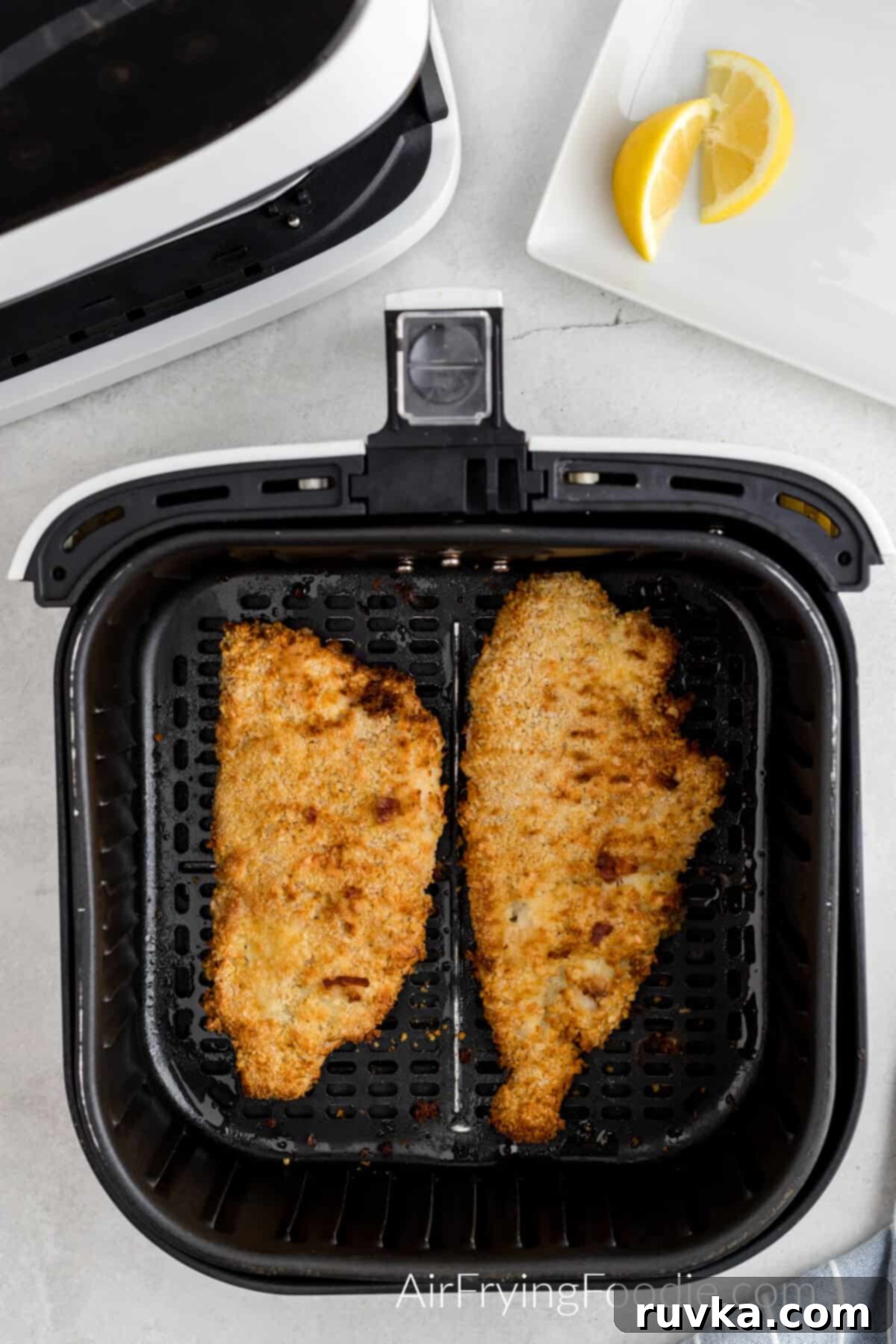 Air Fryer Reheat Crispy Fish Every Time 3 Fried fish fillets arranged neatly in a single layer in an air fryer basket, perfectly positioned for reheating to achieve optimal crispiness.