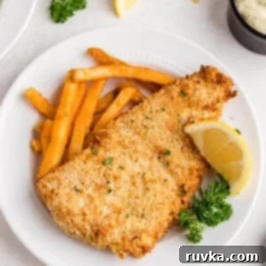 Air Fryer Reheat Crispy Fish Every Time 6 Perfectly reheated fried fish from the air fryer, served with crispy fries and a lemon slice on a white plate.