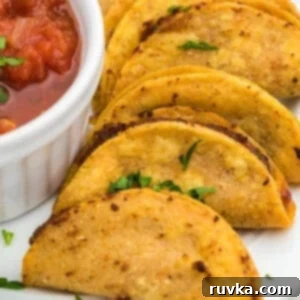 Air Fryer Crispy Taco Bites 9 Air fried mini tacos served on a white plate with a side of salsa for dipping.