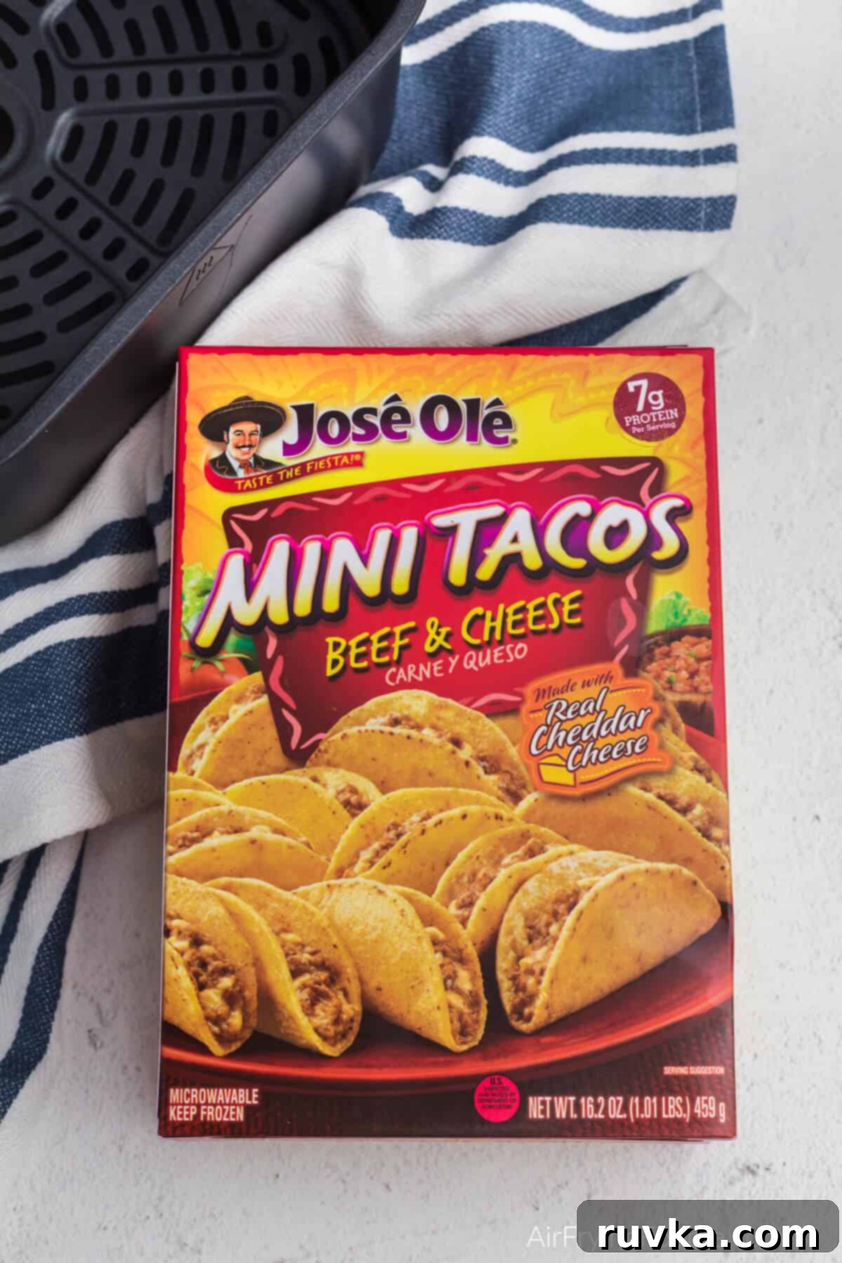Air Fryer Crispy Taco Bites 3 Box of Jose Ole frozen mini tacos made with beef and cheese in the box on a counter with a towel and the basket of the air fryer.