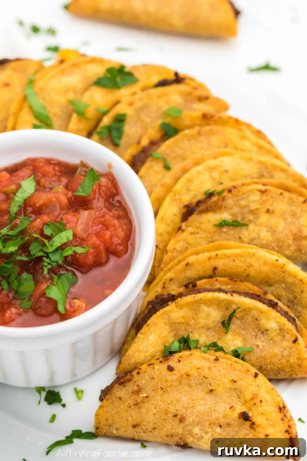 Air Fryer Crispy Taco Bites 7 Air fried mini tacos on a white plate with salsa for dipping.