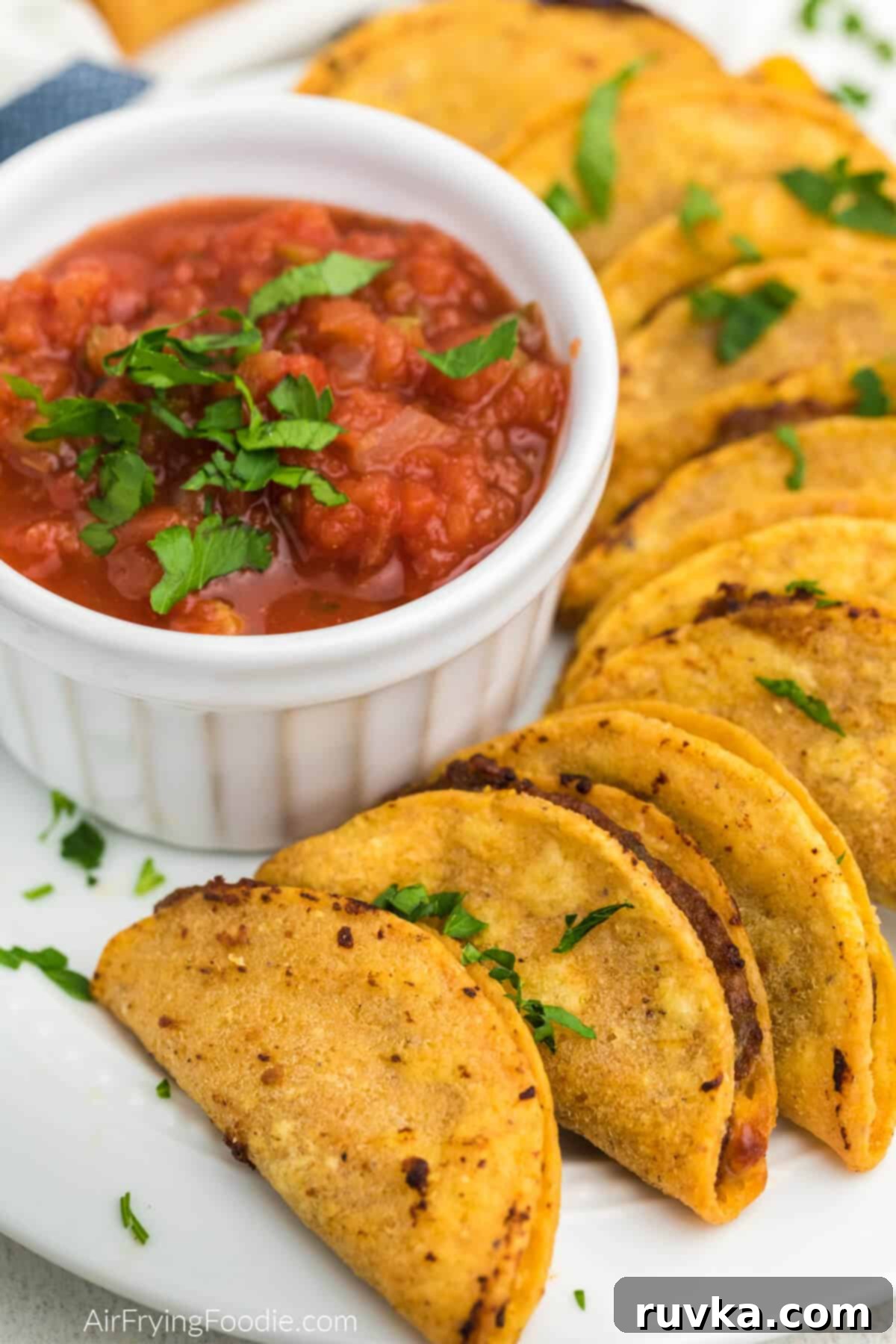 Air Fryer Crispy Taco Bites 8 Plate full of air fried mini tacos with a bowl of salsa for dipping.