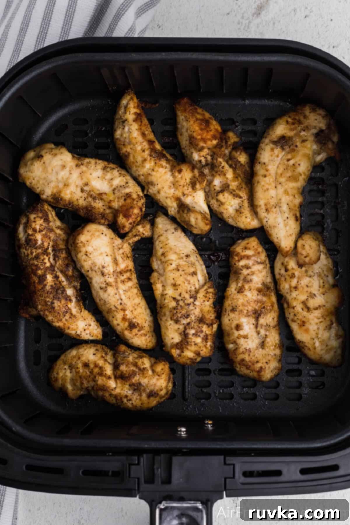 Crispy Air Fryer Chicken Tender Revival 2 Chicken tenders in the air fryer basket in a single layer, ready to be reheated.