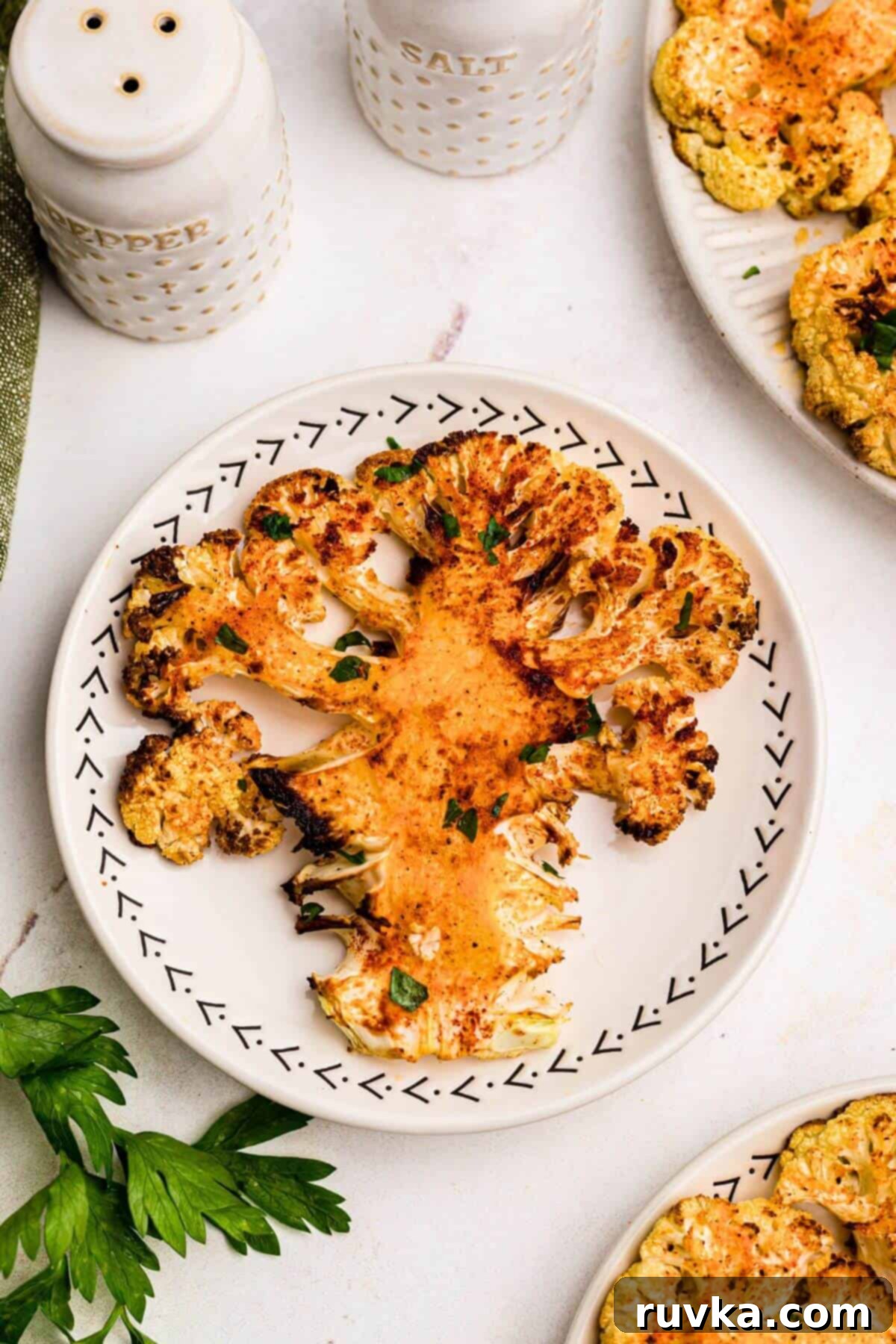 Crispy Air Fryer Cauliflower Steaks 2 Golden crispy cauliflower steak on a plate with a parsley garnish.