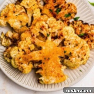 Crispy Air Fryer Cauliflower Steaks 9 Golden cauliflower steaks on a small white plate after being cooked in the air fryer.