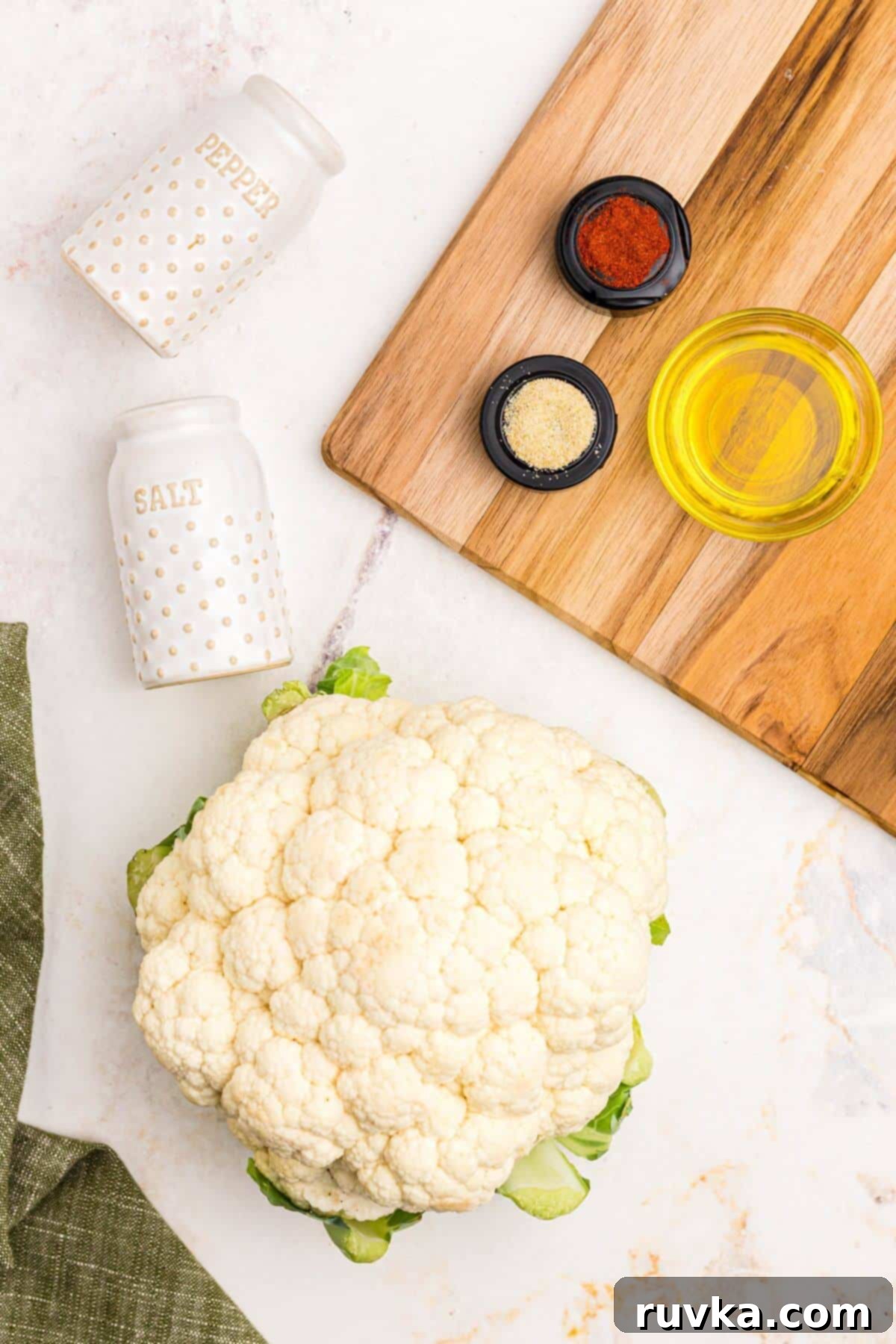 Crispy Air Fryer Cauliflower Steaks 3 Cauliflower head, olive oil, and seasonings on a marble table.