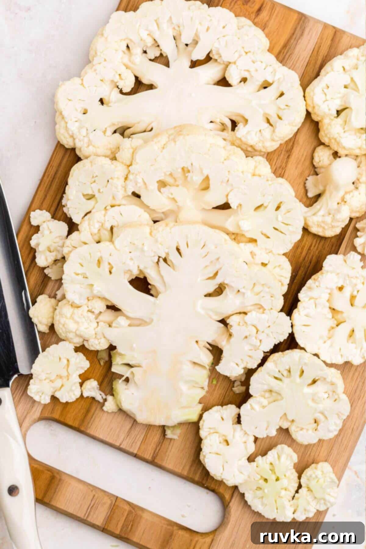 Crispy Air Fryer Cauliflower Steaks 4 Uncooked cauliflower cut into slabs on a wooden cutting board.