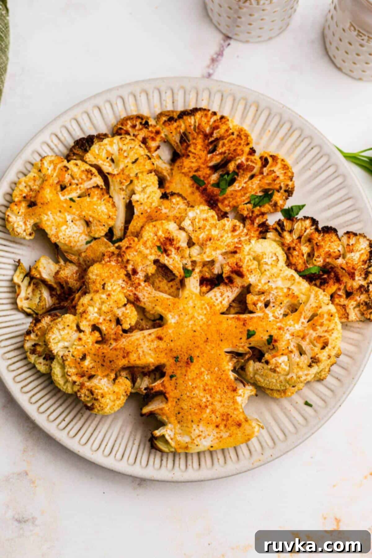 Crispy Air Fryer Cauliflower Steaks 8 Golden cauliflower steaks on a small white plate after being cooked in the air fryer.