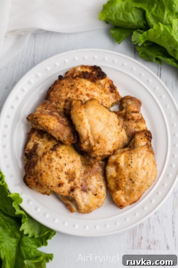 Air Fryer Chicken Thighs Perfection 4 Overhead image of chicken thighs seasoned and cooked on a white plate, ready to be served.
