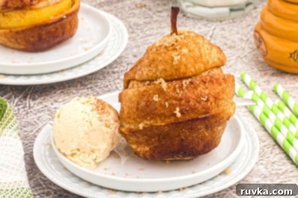 Honey Kissed Air Fried Pears 2 Golden pear wrapped in a layer of puff pastry strips, served on a white plate with vanilla ice cream.