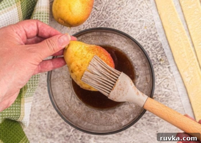 Honey Kissed Air Fried Pears 3 Pastry brush glazing melted butter and brown sugar mixture onto a pear before wrapping it in pastry.