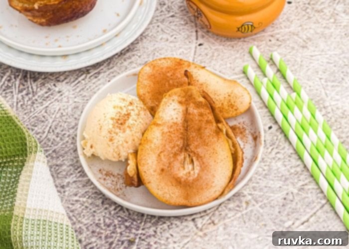 Honey Kissed Air Fried Pears 6 Cooked golden pear, served with vanilla ice cream, and sprinkled with cinnamon, served on a white plate.