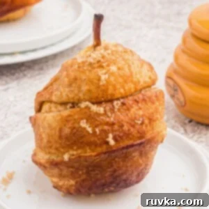 Honey Kissed Air Fried Pears 8 Golden pear wrapped in a puff pastry, sprinkled with brown sugar and served on a white plate.
