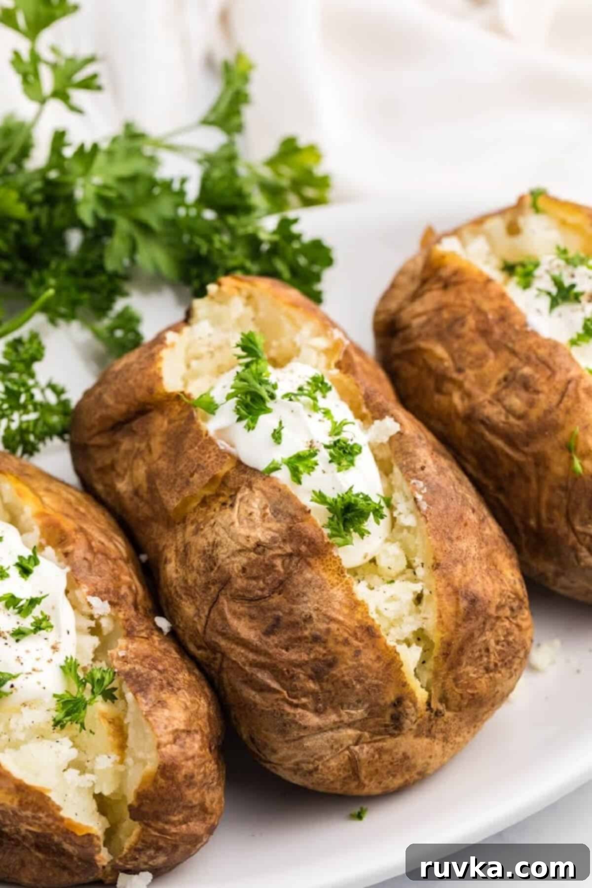Revive Your Baked Potato in the Air Fryer 2 Baked potato reheated in air fryer and topped with toppings on white plate.