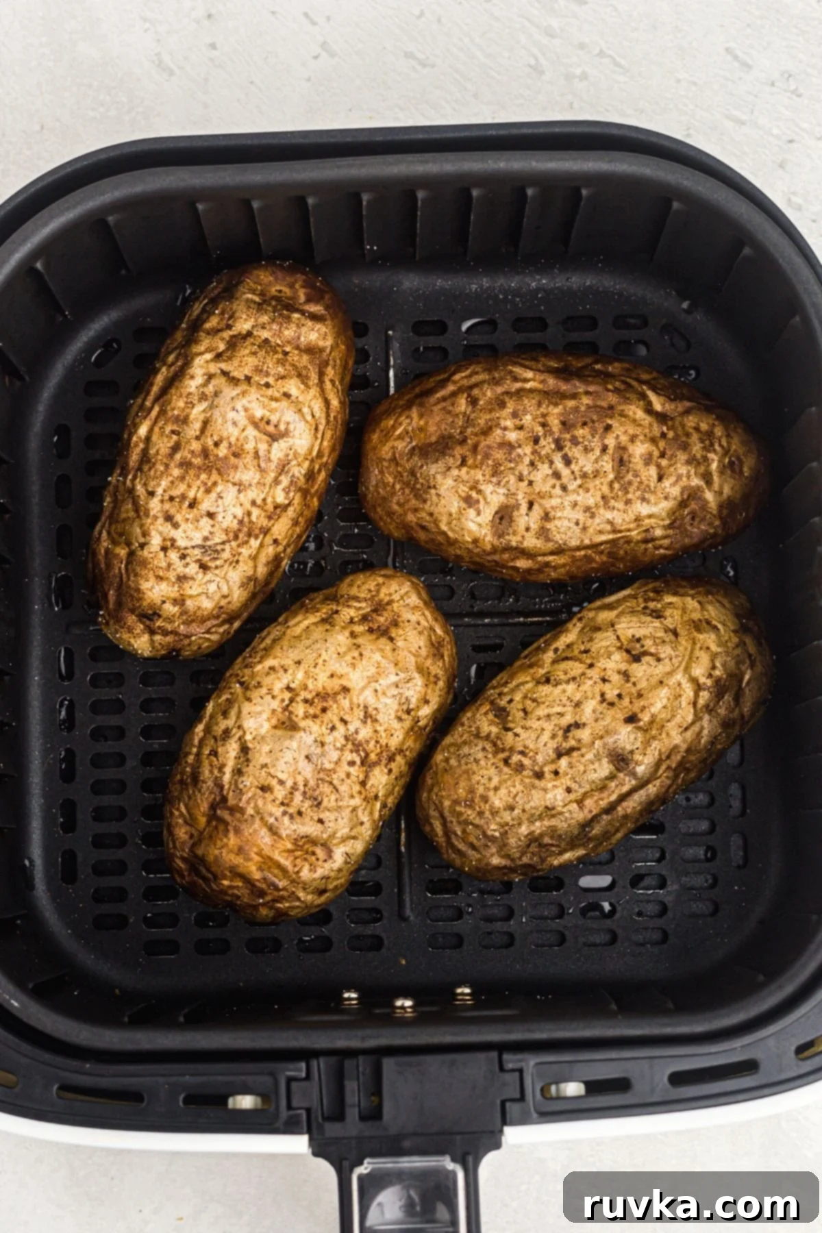 Revive Your Baked Potato in the Air Fryer 4 Four potatoes in the air fryer basket after being cooked.