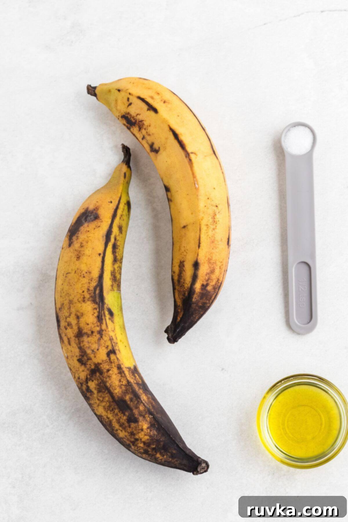 Sweet & Crispy Air Fryer Plantains 3 Plantains, olive oil and salt measured out on a white marble table.