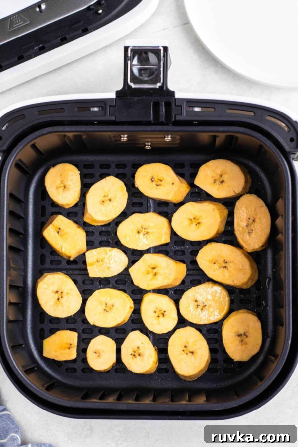 Sweet & Crispy Air Fryer Plantains 6 Plantain slices in the air fryer before being cooked.