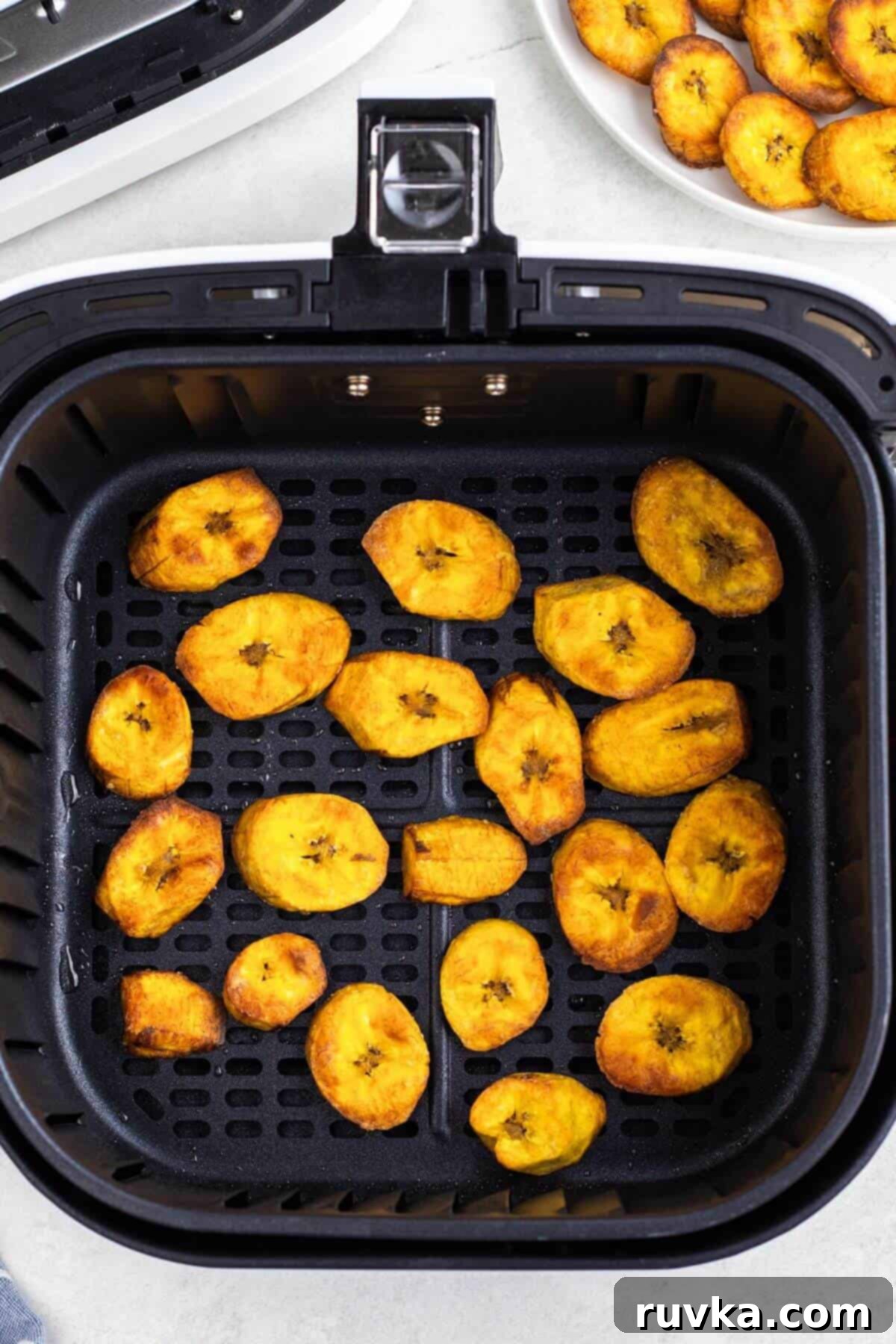 Sweet & Crispy Air Fryer Plantains 7 Golden brown plantain slices in the air fryer basket after being cooked.