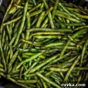 Crispy Air Fryer Frozen Green Beans 10 Seasoned green beans in the air fryer basket after being cooked.