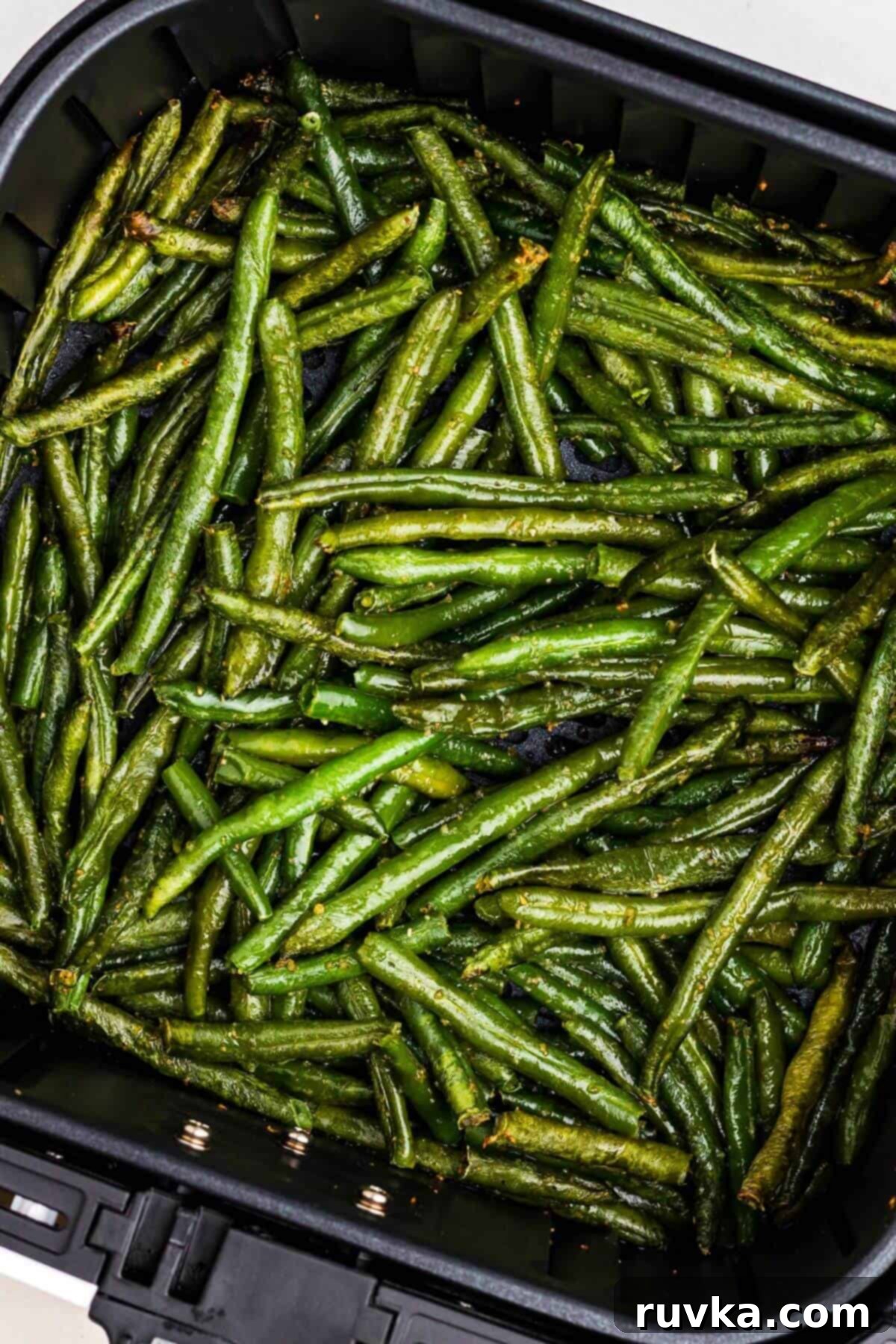 Crispy Air Fryer Frozen Green Beans 7 Seasoned green beans in the air fryer basket after being cooked.