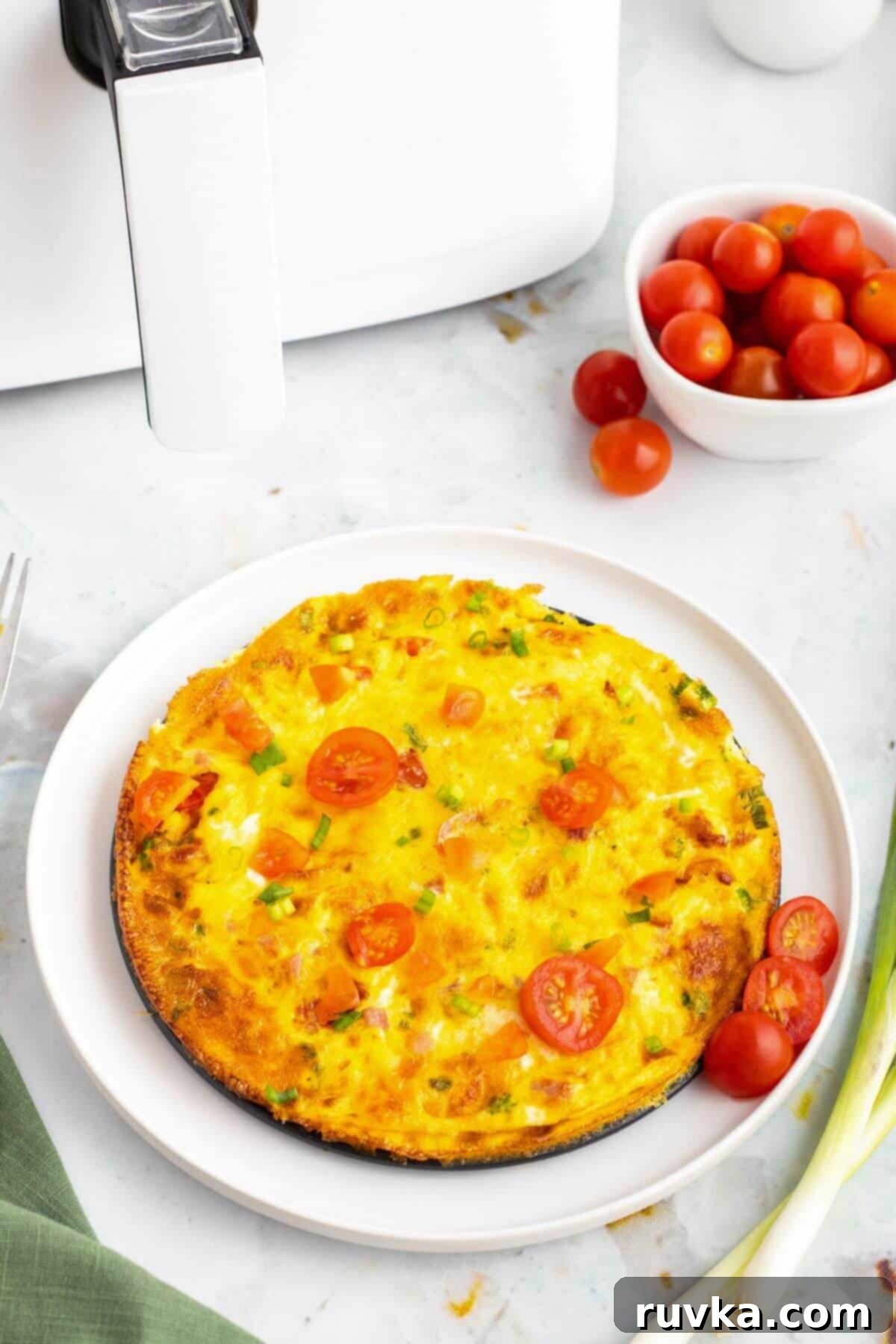 Easy Air Fryer Omelette 2 A vibrant, fluffy yellow omelette, perfectly cooked in the air fryer, resting on a crisp white plate, garnished with fresh herbs.