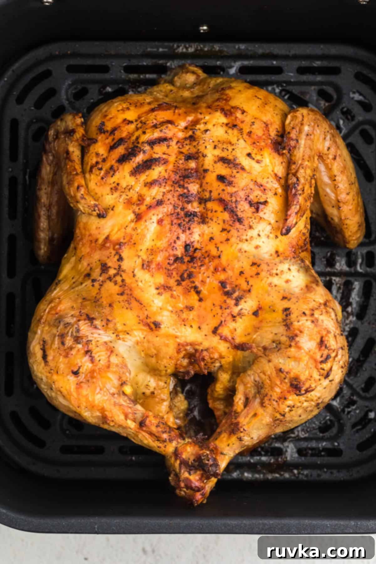 Air Fryer Magic: Reheating Rotisserie Chicken to Perfection 2 Rotisserie chicken in air fryer basket ready to be reheated, showcasing golden brown skin and tender appearance.