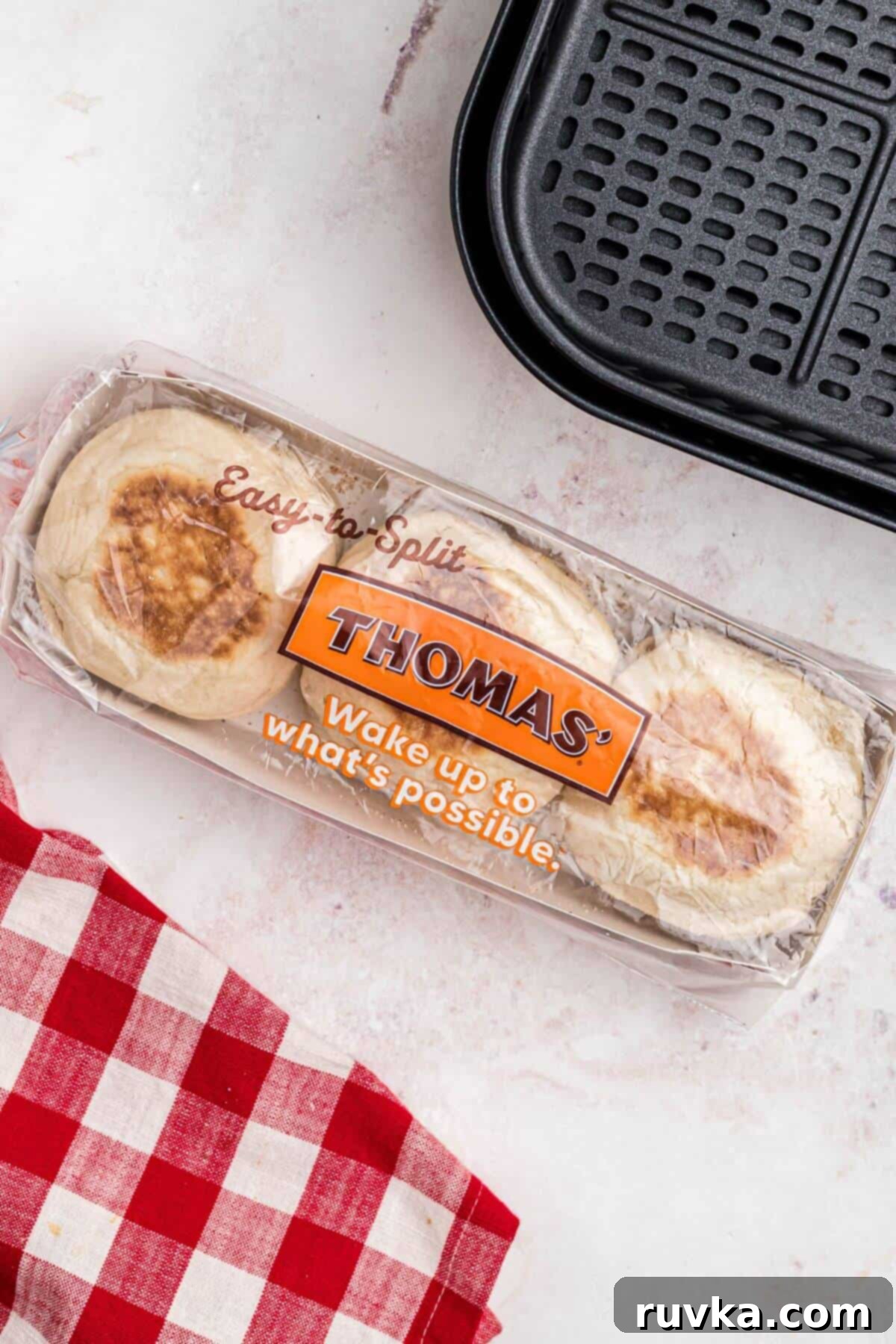 Homemade Air Fryer English Muffins 3 Package of English muffins on a marble table with a red checkered linen.