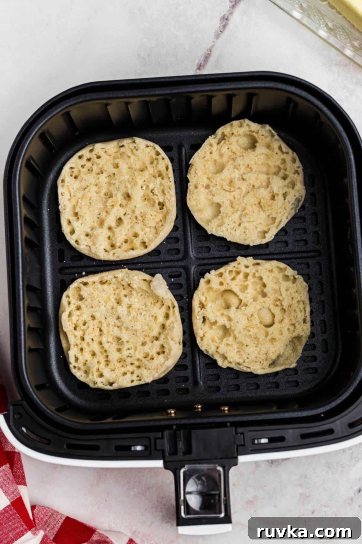 Homemade Air Fryer English Muffins 4 English muffins pulled apart and placed in the air fryer basket before cooking.