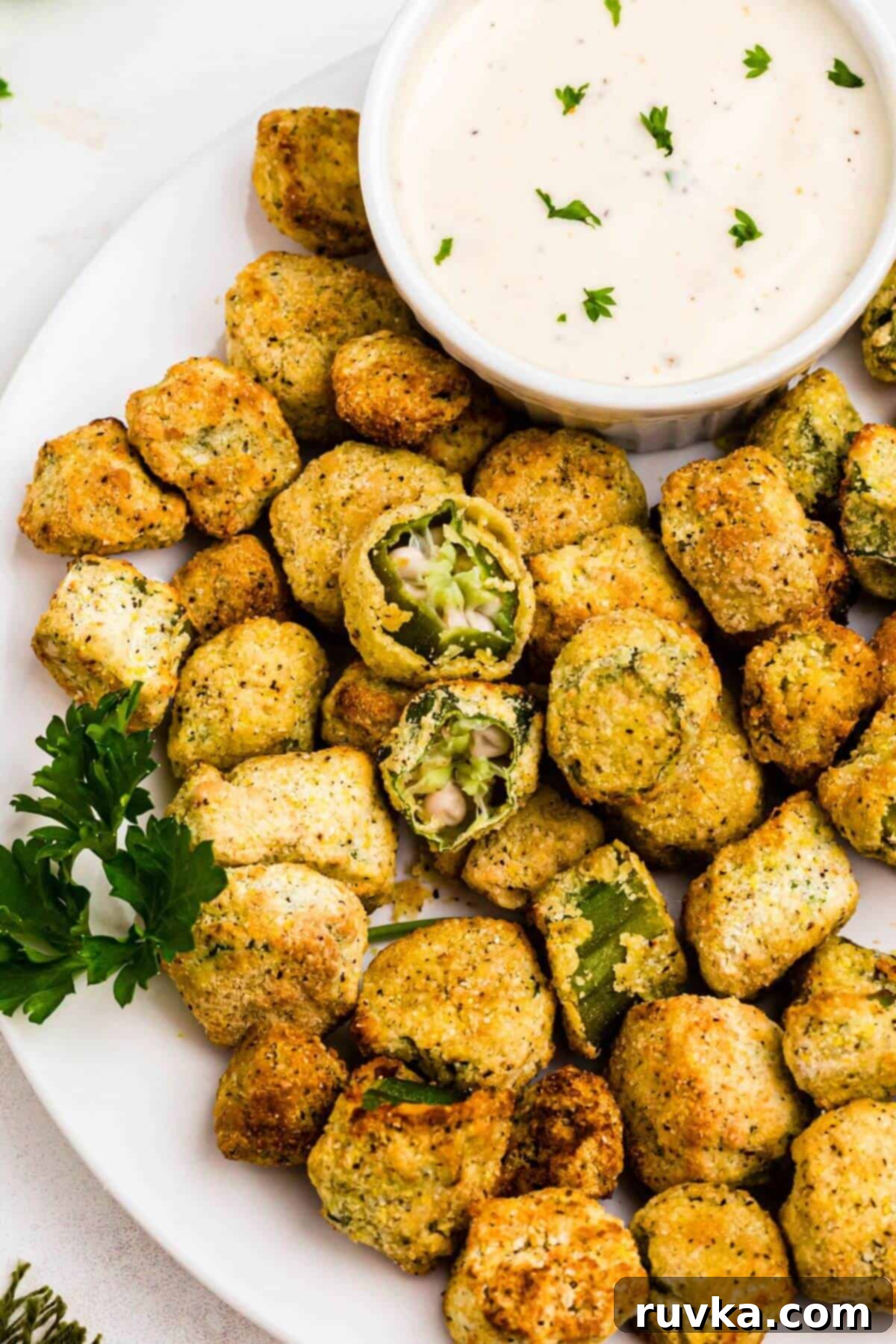 Air Fryer Magic for Frozen Okra 2 Golden brown breaded fried okra on a white plate with ranch dressing dipping sauce.