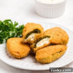 Crispy Air Fryer Frozen Jalapeno Poppers 9 Golden crispy breaded jalapeno poppers on a small white plate.
