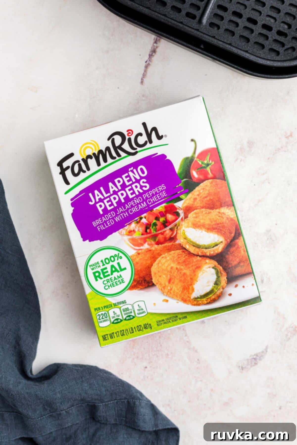 Crispy Air Fryer Frozen Jalapeno Poppers 3 One box of frozen jalapeno poppers with an air fryer basket on a marble table.