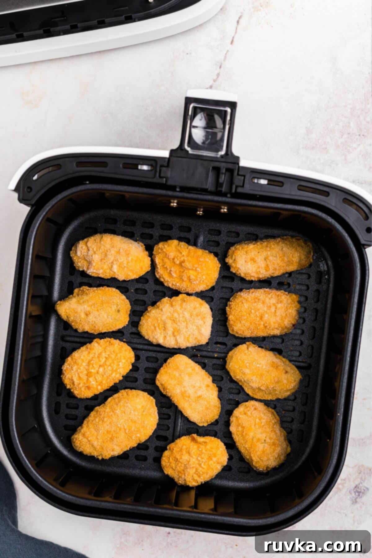 Crispy Air Fryer Frozen Jalapeno Poppers 4 Frozen jalapeno poppers in an air fryer basket before being cooked.
