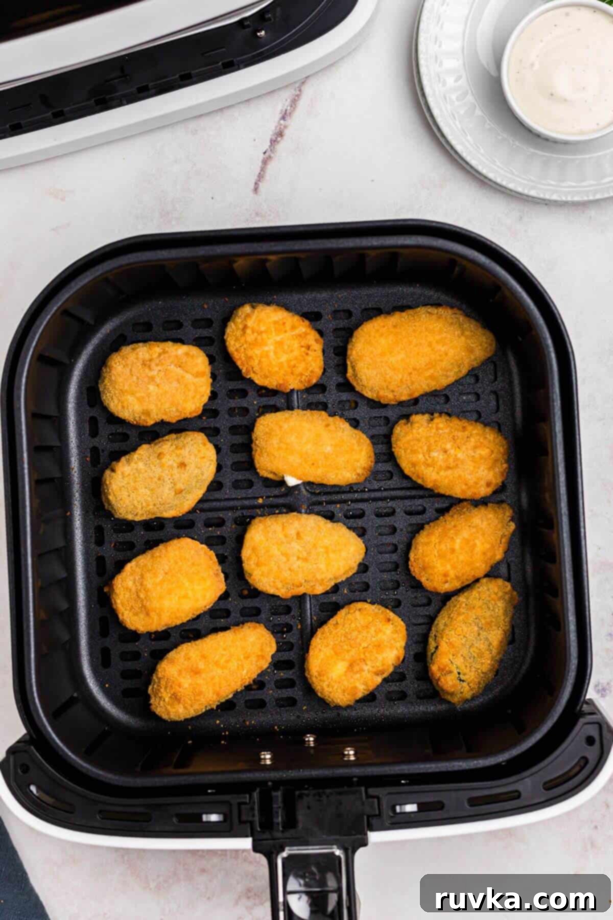 Crispy Air Fryer Frozen Jalapeno Poppers 5 Golden crispy breaded jalapeno poppers in the air fryer basket after being cooked.