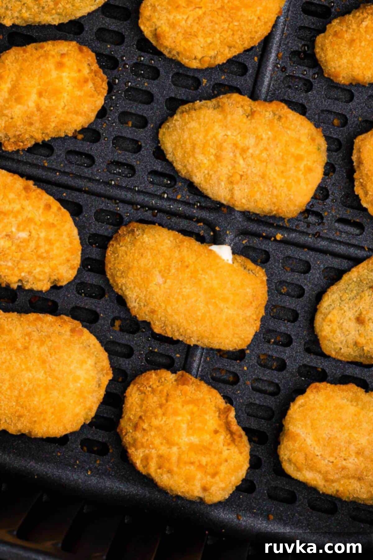 Crispy Air Fryer Frozen Jalapeno Poppers 6 Golden crispy breaded jalapeno poppers in the air fryer basket after being cooked.