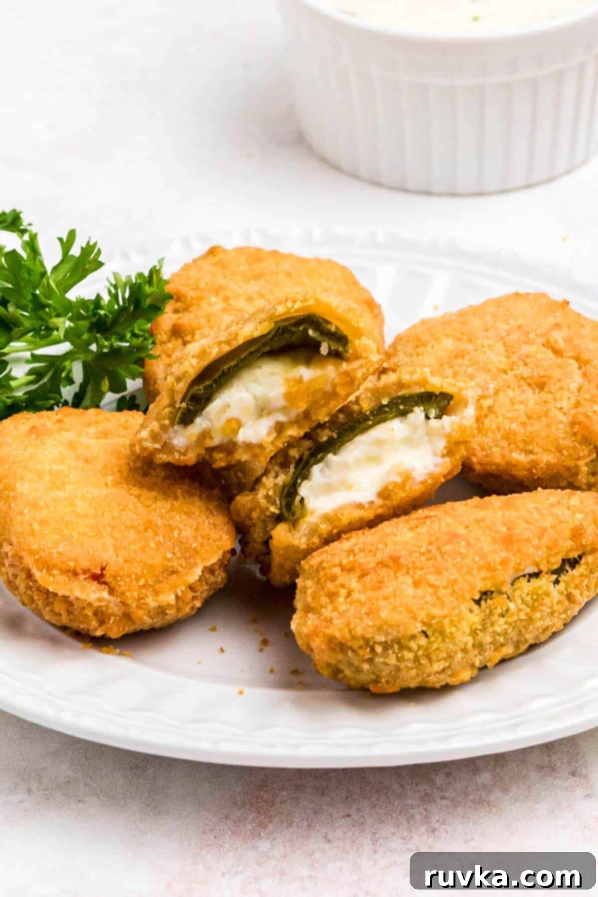 Crispy Air Fryer Frozen Jalapeno Poppers 7 Golden crispy breaded jalapeno poppers on a small white plate.