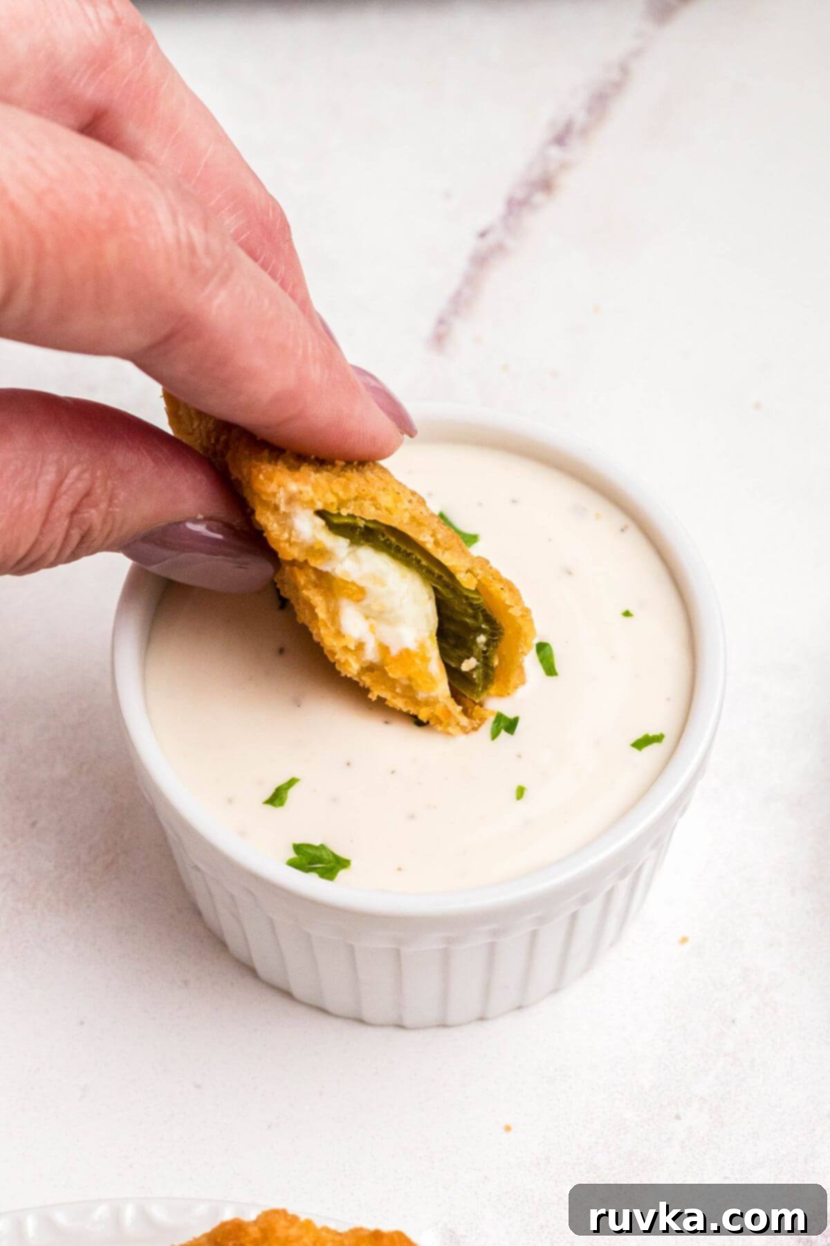 Crispy Air Fryer Frozen Jalapeno Poppers 8 Golden crispy breaded jalapeno popper being dipped into ranch dressing.