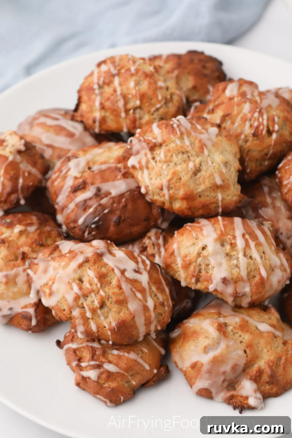 15 Cozy Autumn Air Fryer Desserts You'll Adore 15 Apple fritters made in the air fryer and stacked on a white plate.