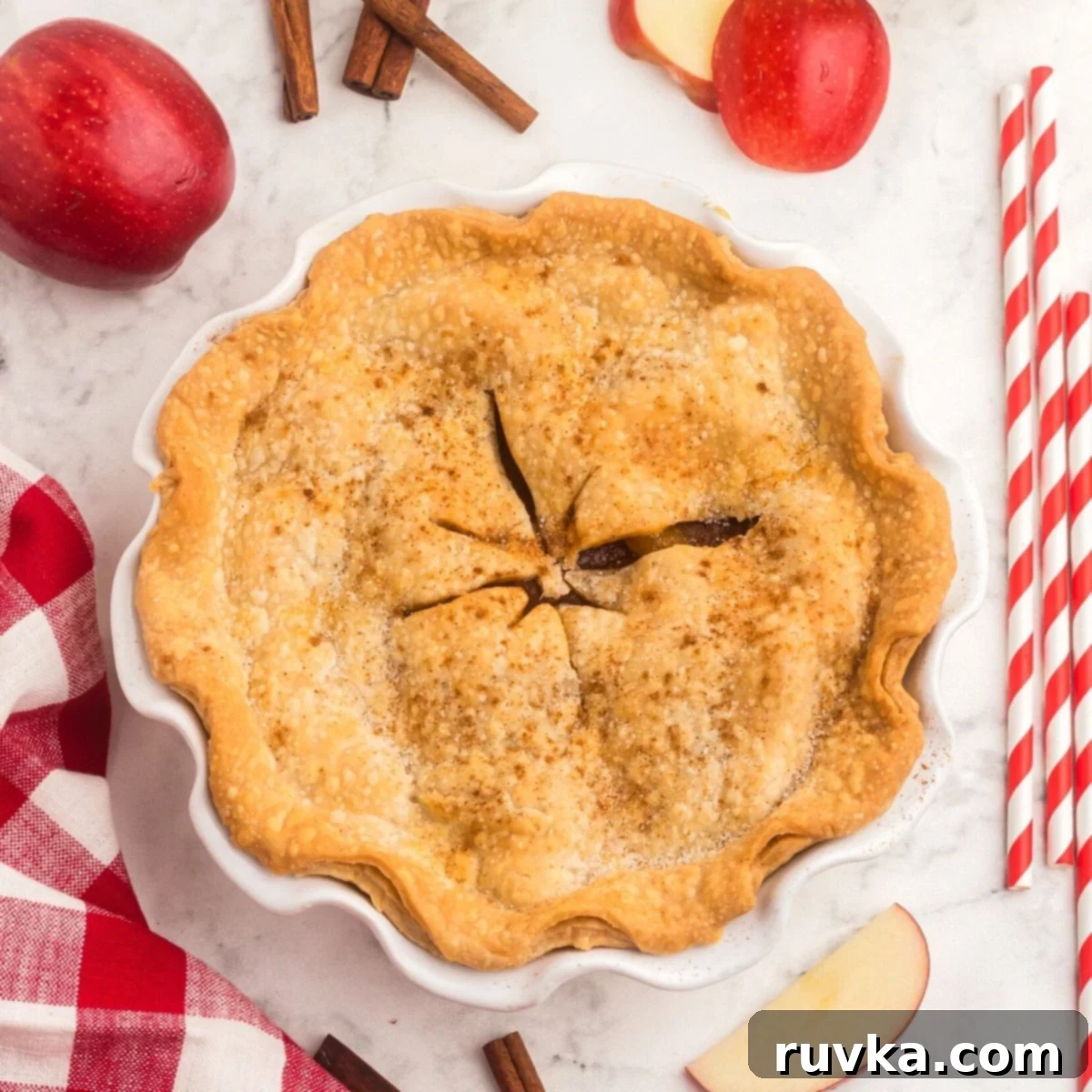 15 Cozy Autumn Air Fryer Desserts You'll Adore 4 Golden baked apple pie, with red apples and red and white straws on the table.
