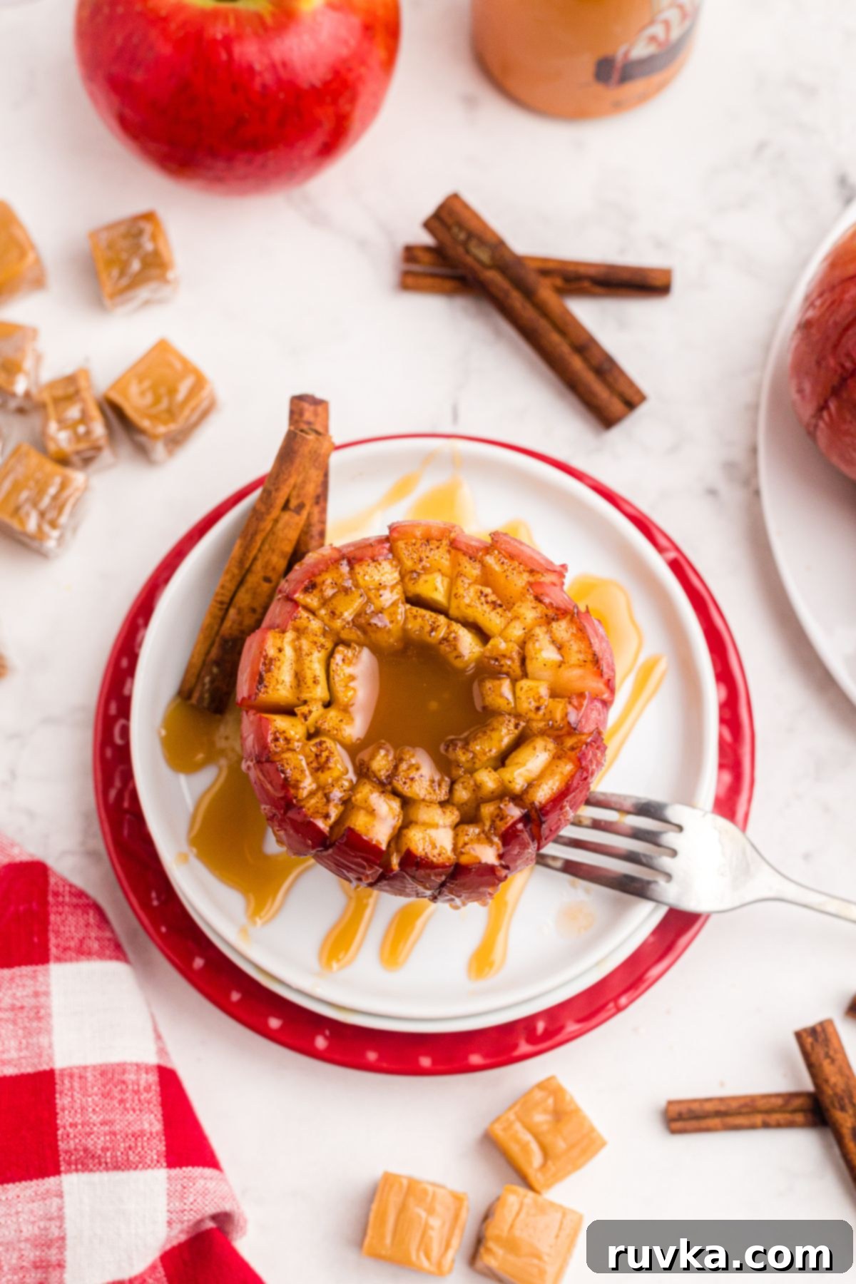 15 Cozy Autumn Air Fryer Desserts You'll Adore 5 Blooming apple on a white plate drizzled with caramel sauce with a fork to the side.