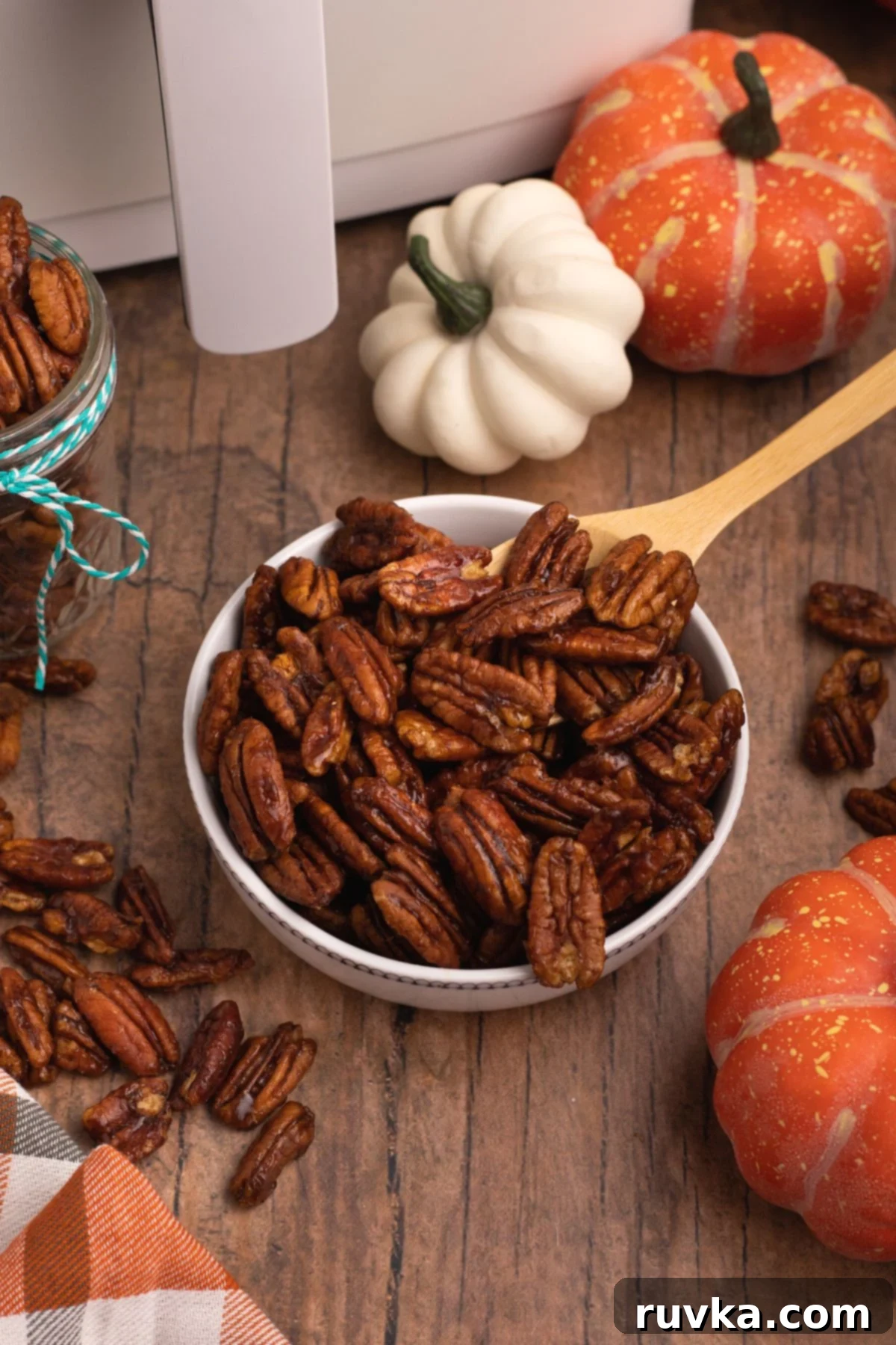 15 Cozy Autumn Air Fryer Desserts You'll Adore 7 Pumpkin spice pecans in a bowl with a wooden spoon scooping some out.