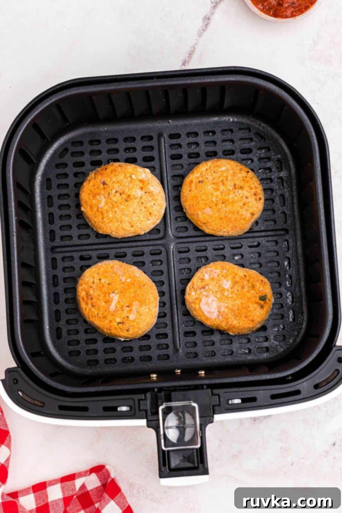 Crispy Air Fryer Frozen Crab Cakes 4 Frozen golden crab cakes in the air fryer basket before being air fried.