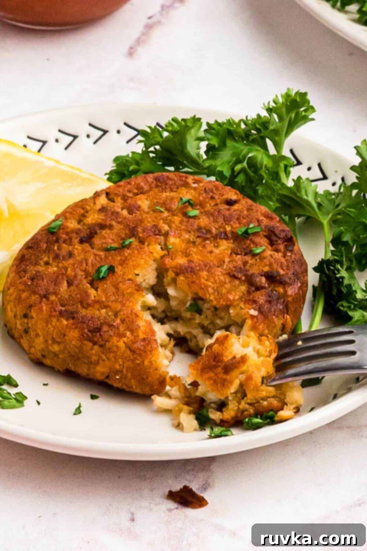 Crispy Air Fryer Frozen Crab Cakes 7 Golden crispy crab cake on a small plate with a fork taking a small piece.