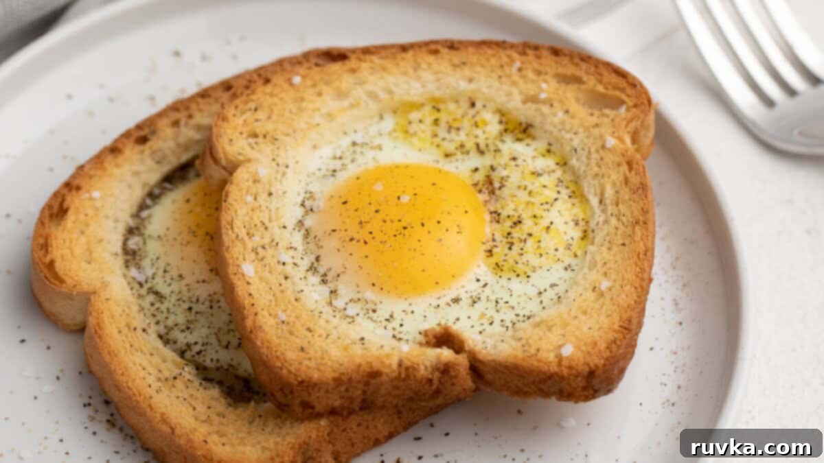 15 Effortless Breakfasts for a Perfect Start 11 A perfectly cooked air fryer egg in a basket (or egg in a hole), garnished with a sprinkle of salt and pepper, served on a pristine white plate for a simple yet elegant breakfast.